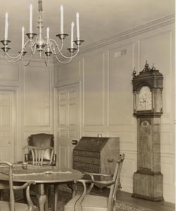old sepia photo of an antique tall-case clock in a large parlor